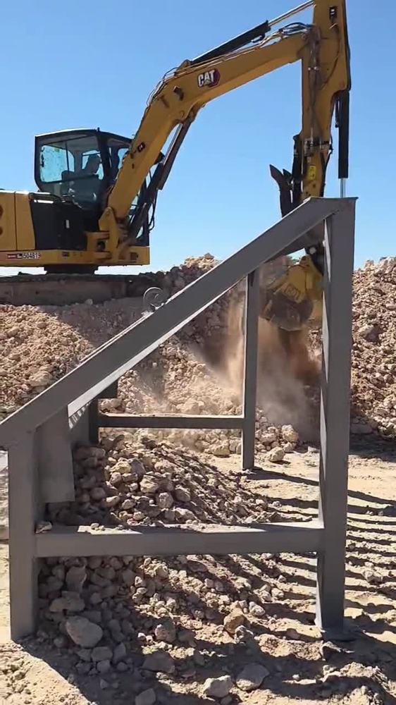 Excavator dumping rock onto a custom grizzly screen